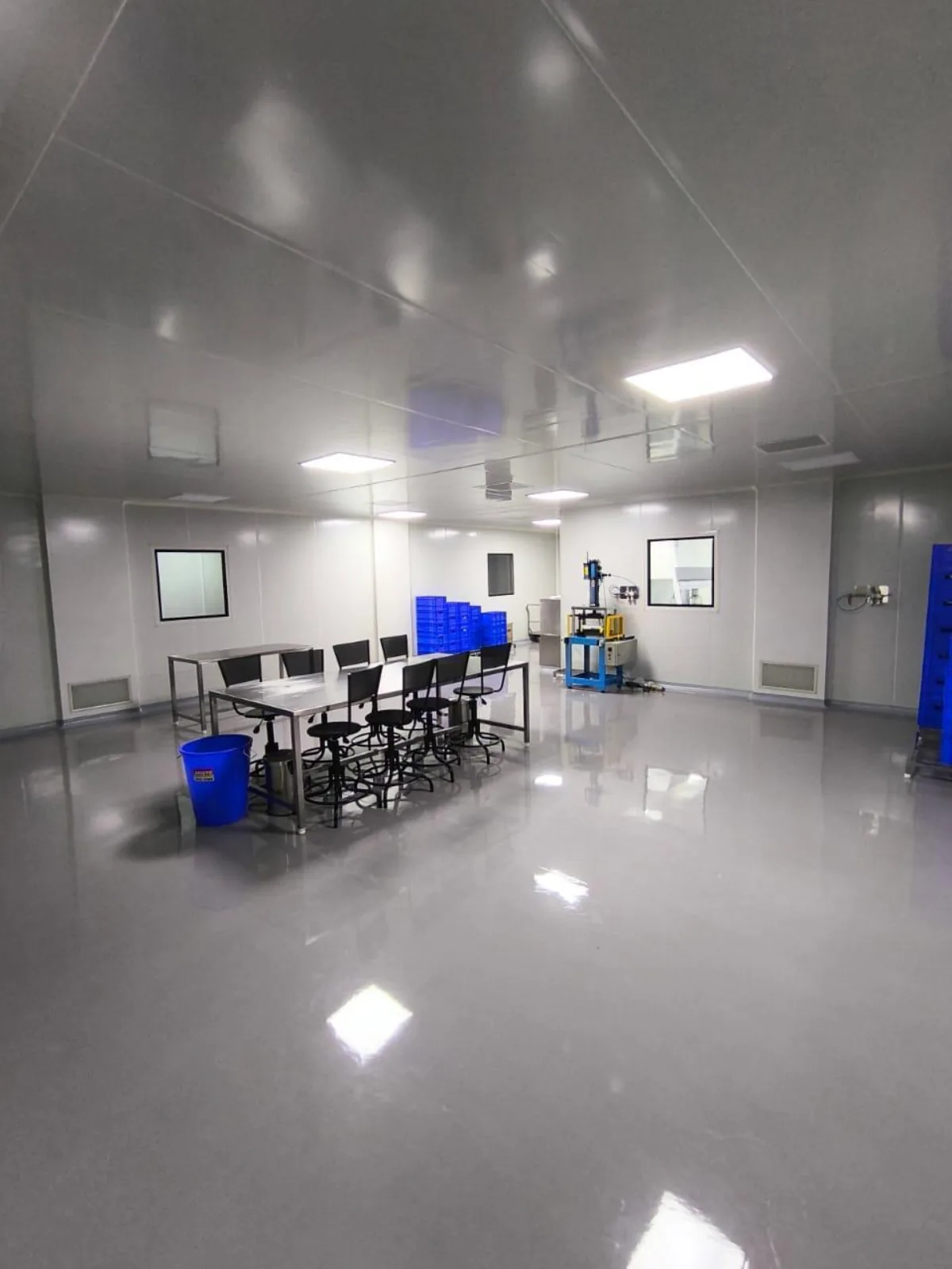 Completed cleanroom production hall with modular wall panels, flush LED ceiling lighting, terminal filter grilles, stainless work benches and coved epoxy flooring