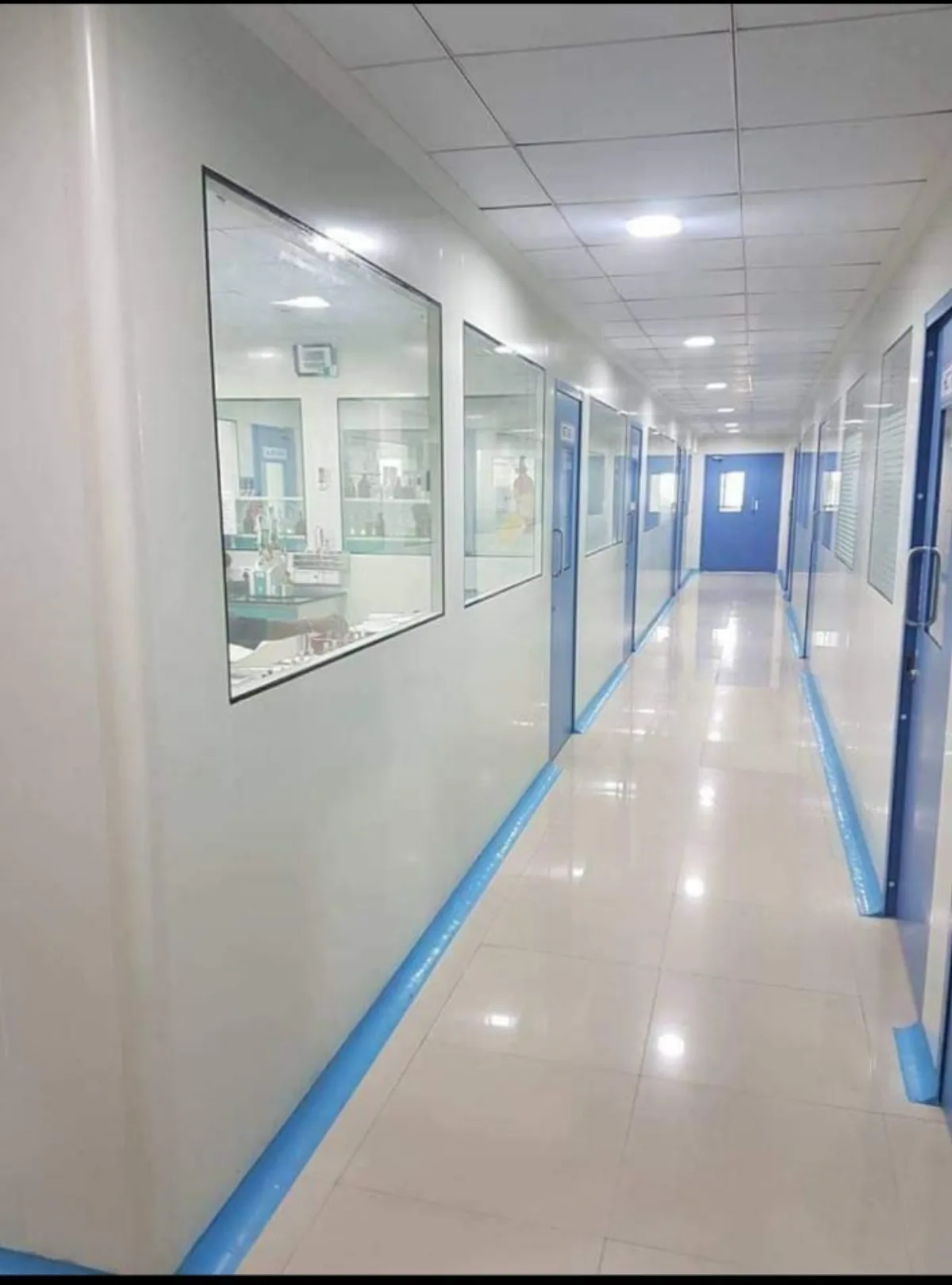 Cleanroom laboratory corridor with observation glazing, controlled blue doors and seamless washable wall and floor finishes